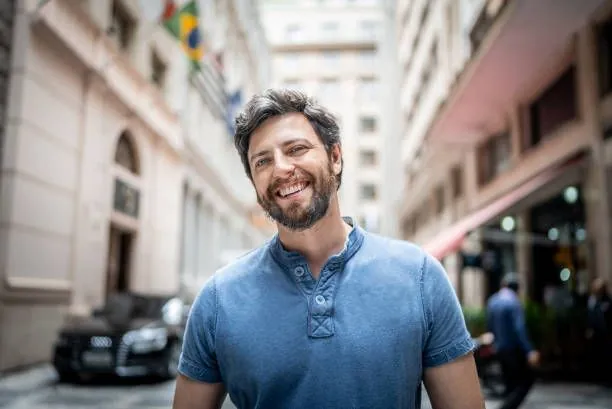 Man in blue shirt smiling widely to take a good dating profile photo