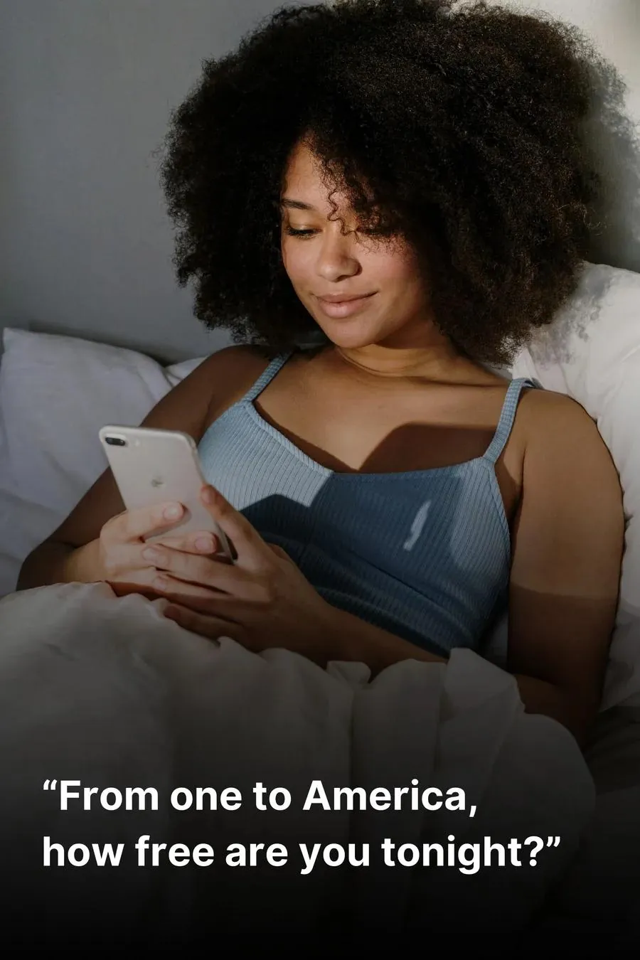 Woman lying in bed and smiling while texting someone on her phone